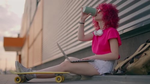 Young Woman Uses Laptop Outside Urban Building