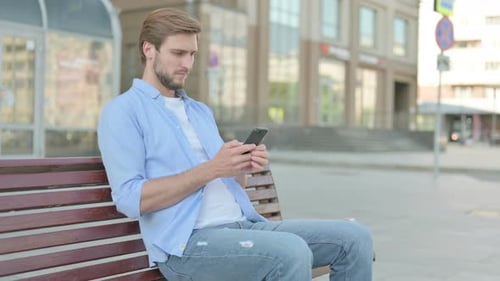 Handsome Man Using Smartphone on Park Bench