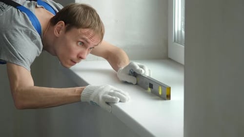 Man Checking Level on White Window Sill