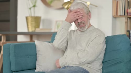 Senior Man Suffering from Headache While Sitting on Couch