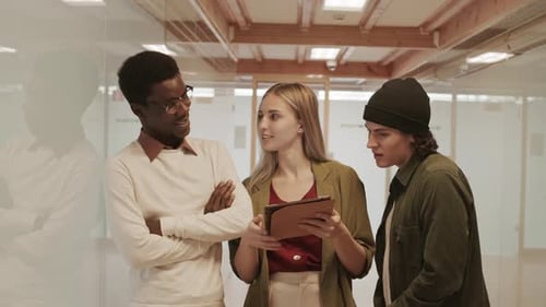 Office Colleagues Discussing Tablet Information in Modern Workplace