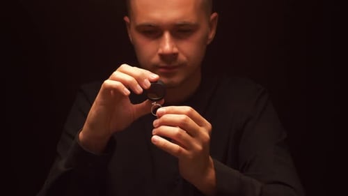 Man Inspecting Diamond Ring with Small Tool