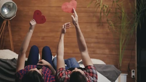Romantic Couple Hold Paper Hearts Lying Together Indoors