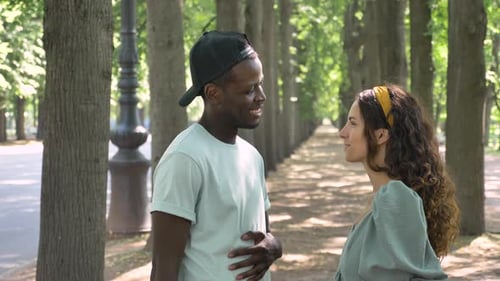 Young Couple Chatting in Sunny Tree-lined Park