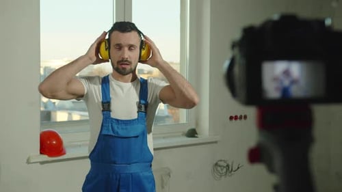 Man in Overalls Puts on Ear Protection