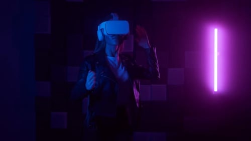 Jeune femme portant un casque de réalité virtuelle exécutant une danse de style robot sur fond de néon