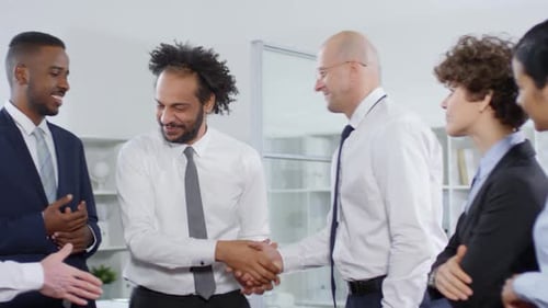 Businessman Shaking Hands with Colleagues after Meeting in Office