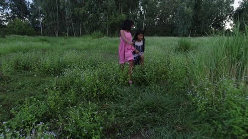 4K Two little girls running around the park