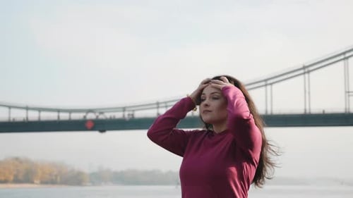 Woman Puts Hair Up by a River