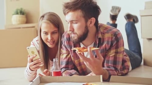 Couple Eating Pizza in New Home with Boxes