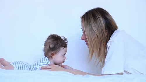 Smiling Mother With Happy Infant on White Bed