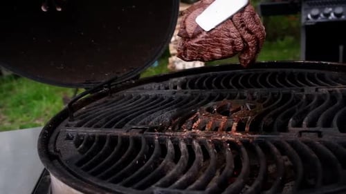 Juicy fried steak is turned over on a hot grill