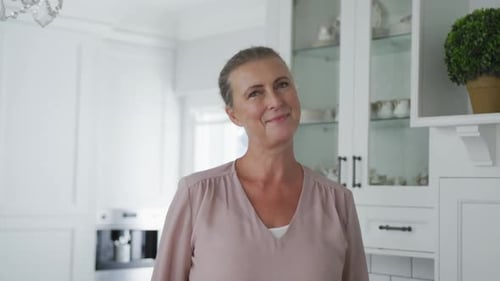 Mature Woman Smiling in Bright White Kitchen