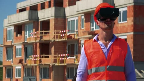 Construction Worker Uses Virtual Reality Glasses and Looks Around in Front of Building Site
