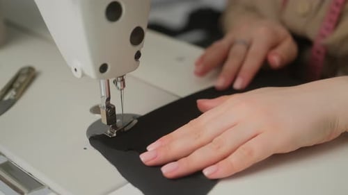 Stitching on sewing machine. Tailor sews on sewing machine. Close-up of woman's hand