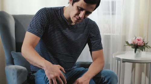 Un homme au genou douloureux assis sur un fauteuil