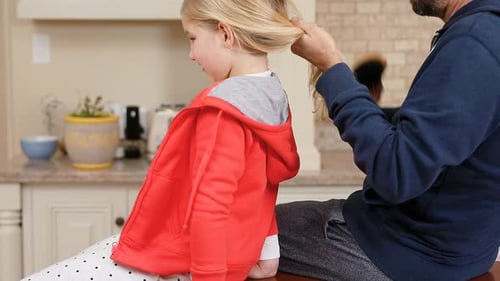 Caring Father Brushing Daughter's Hair at Home