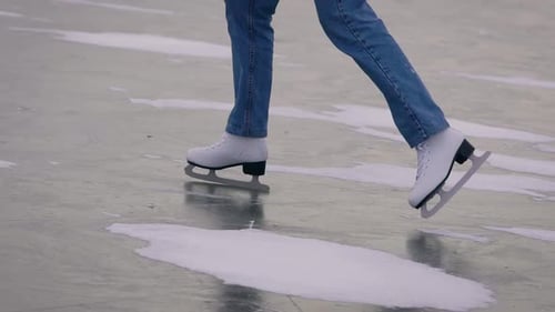 Ice Skating on a Frozen Lake. In the Frame, Close-up of Legs in Jeans and White Skates.