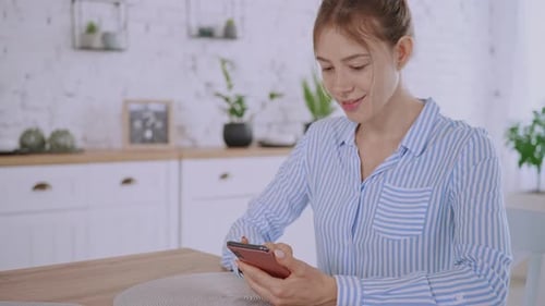 Woman Using Phone at Table Indoors