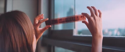 Woman Inspecting a Strip of Film by Window