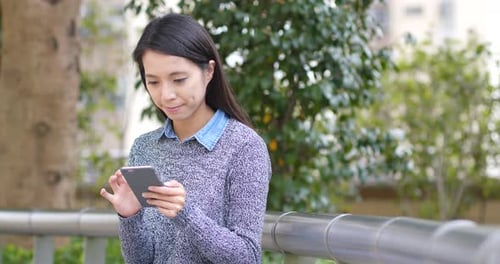 Woman Using Mobile Phone in Urban Park Setting