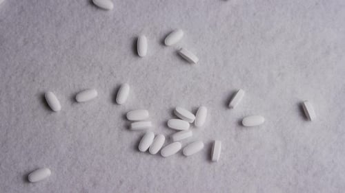 Scattered White Pills on Gray Surface