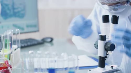 Close Up Dolly Footage of Laboratory Technician Looking Into the Microscope