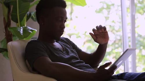 Young Adult Using Tablet Device At Home