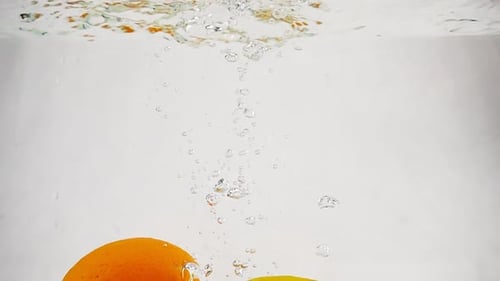 Bright Lemon and Orange Fall Into the Water with Bubbles. Fruit Citrus in Slow Motion on Isolated