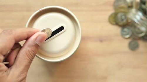 Hand Saving Coins in Piggy Bank at Home