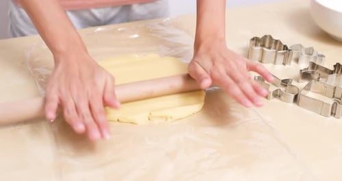 Hands rolling cookie dough with rolling pin