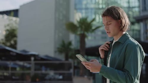 Handsome Guy Walking on Street and Using Smartphone