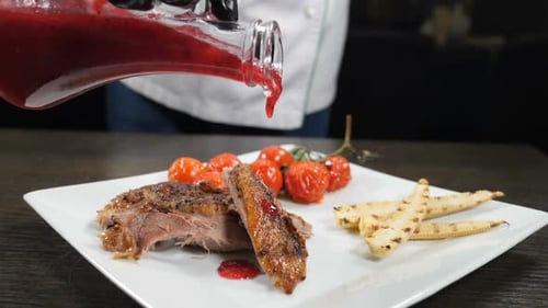 Fine Cuisine. Cooking in Restaurant. Pouring Delicious Sauce Over Roast Duck, Slow Motion. Liquid