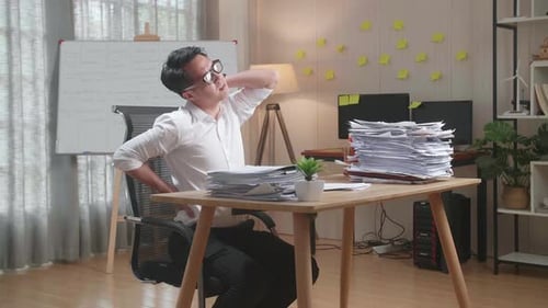 Asian Man Having Backache While Working Hard With Documents At The Office