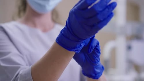 Unrecognizable Doctor in Coronavirus Face Mask Putting on Gloves in Slow Motion