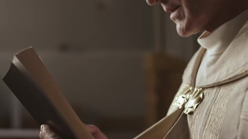 Adult Reading Ceremonial Book in Dark Indoor Setting
