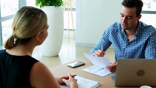 Man and Woman Discussing Business Documents in Office