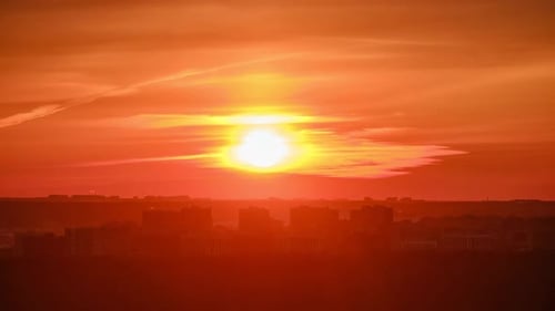 Sunset in a haze of thick clouds over the houses in the urban landscape, time lapse