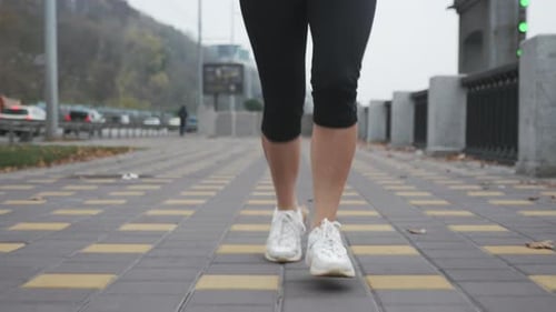 Sports woman athlete running and doing fitness exercises on bank of downtown