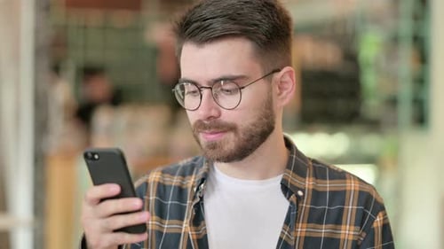 Young Adult Man Using Smartphone Indoors
