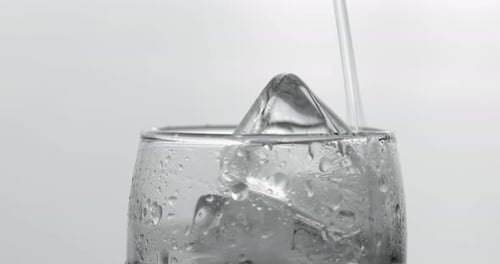 Pouring Clear Liquid Into Glass With Ice