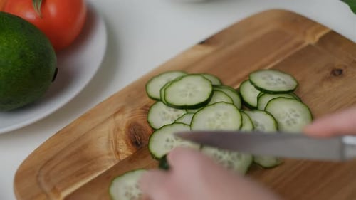 Close-up of Female hands cut a cucumber Cooking Salad.