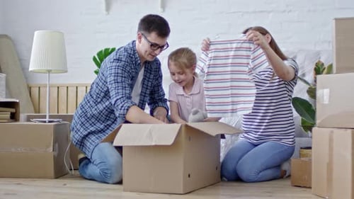 Família jovem desempacotando roupas em casa nova