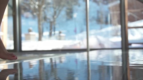 Nahaufnahme einer Frau, die in einem luxuriösen Spa-Resort in einen Pool tritt.