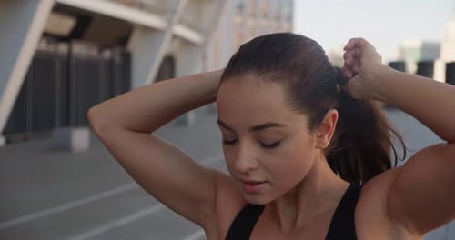 Woman Ties Ponytail on Urban Running Track