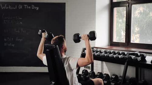 Athlète barbu, homme athlétique, culturiste, entraînement des épaules dans la salle de gym avec des haltères