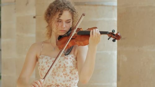 Woman Plays Violin Outdoors on Sunny Day