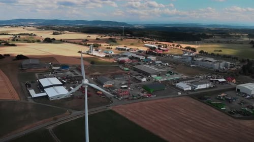 Windmill with rotating blades against industrial area