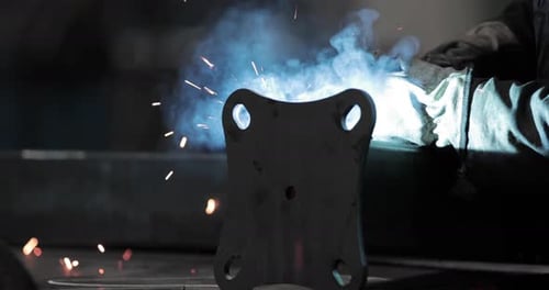 Arbeiter schweißt Metallplatte an Stahlrohr in einer Industriefabrik - Nahaufnahme, Schieberschuss