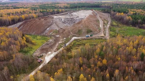 Landfill. A Huge Pile of Garbage Surrounded By Forest. Garbage Trucks Carry Garbage To a Landfill.